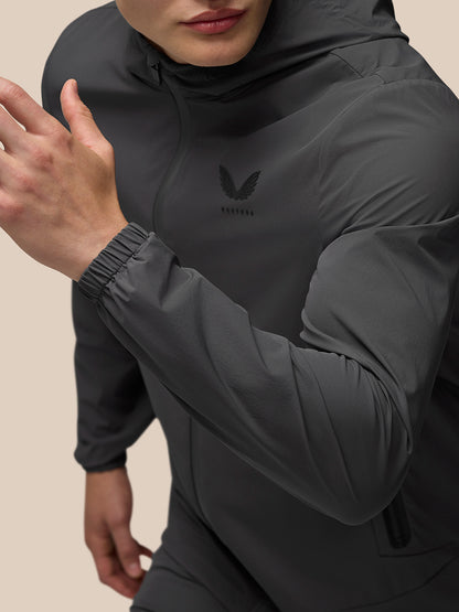Close up of charcoal Lightweight Flex Jacket with hood and left chest branding.