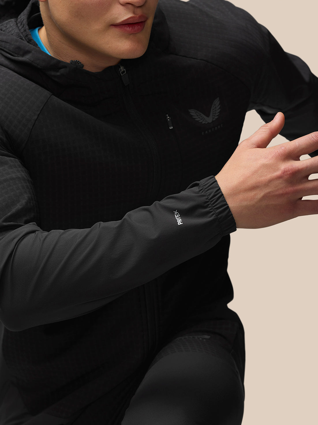 Full body view of a male model in black Flex Winterised Jacket with hood down, blue shirt visible at the neck