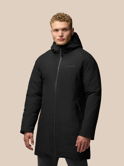 Male model wearing black longline hooded jacket with front zip and external zip pockets