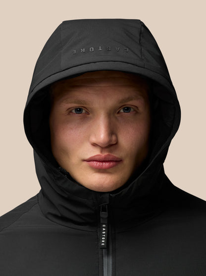 Close-up of a person wearing a black hooded jacket with a center zipper and CASTORE branding on the zipper pull.