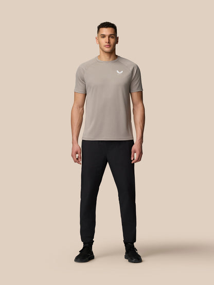 Full-body shot of a male model wearing black Adapt Training Joggers with a light brown top.