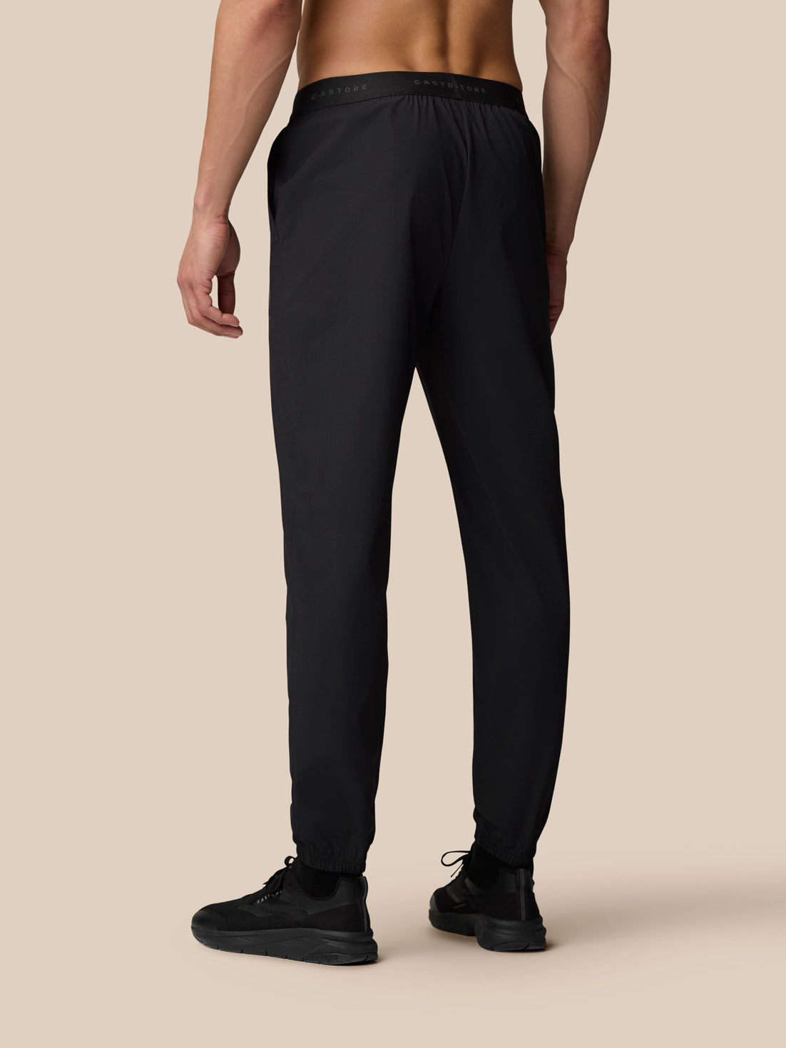 Back view of a man wearing black Adapt Training Joggers with a drawcord waistband and zip hems