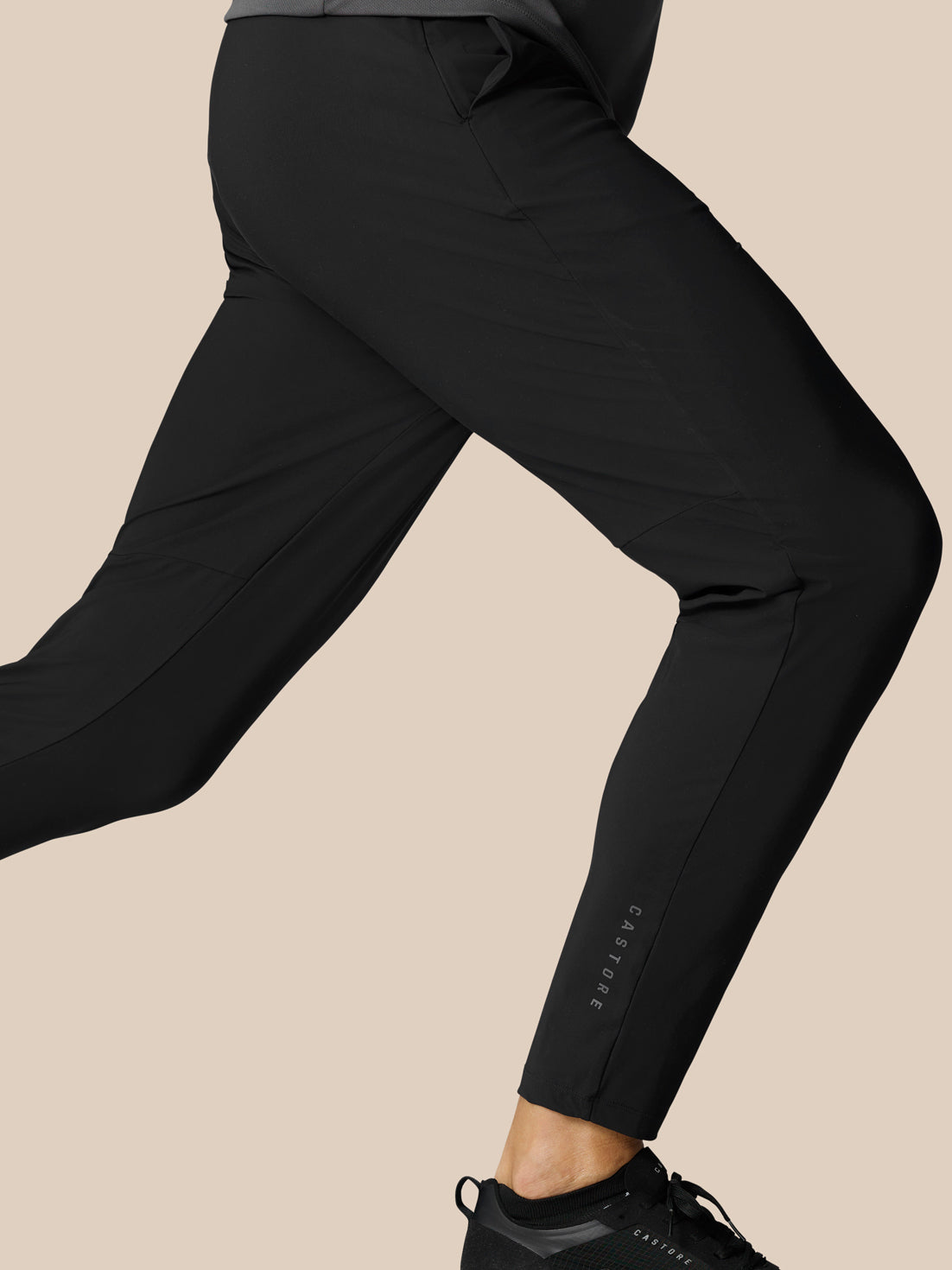 Close-up of the lower leg of black Adapt Tech Training Trousers showing the tapered fit and subtle ankle logo