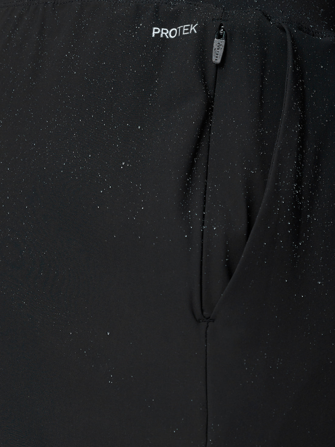 Close-up of black Adapt Tech Training Trousers with a zippered pocket and water droplets on fabric