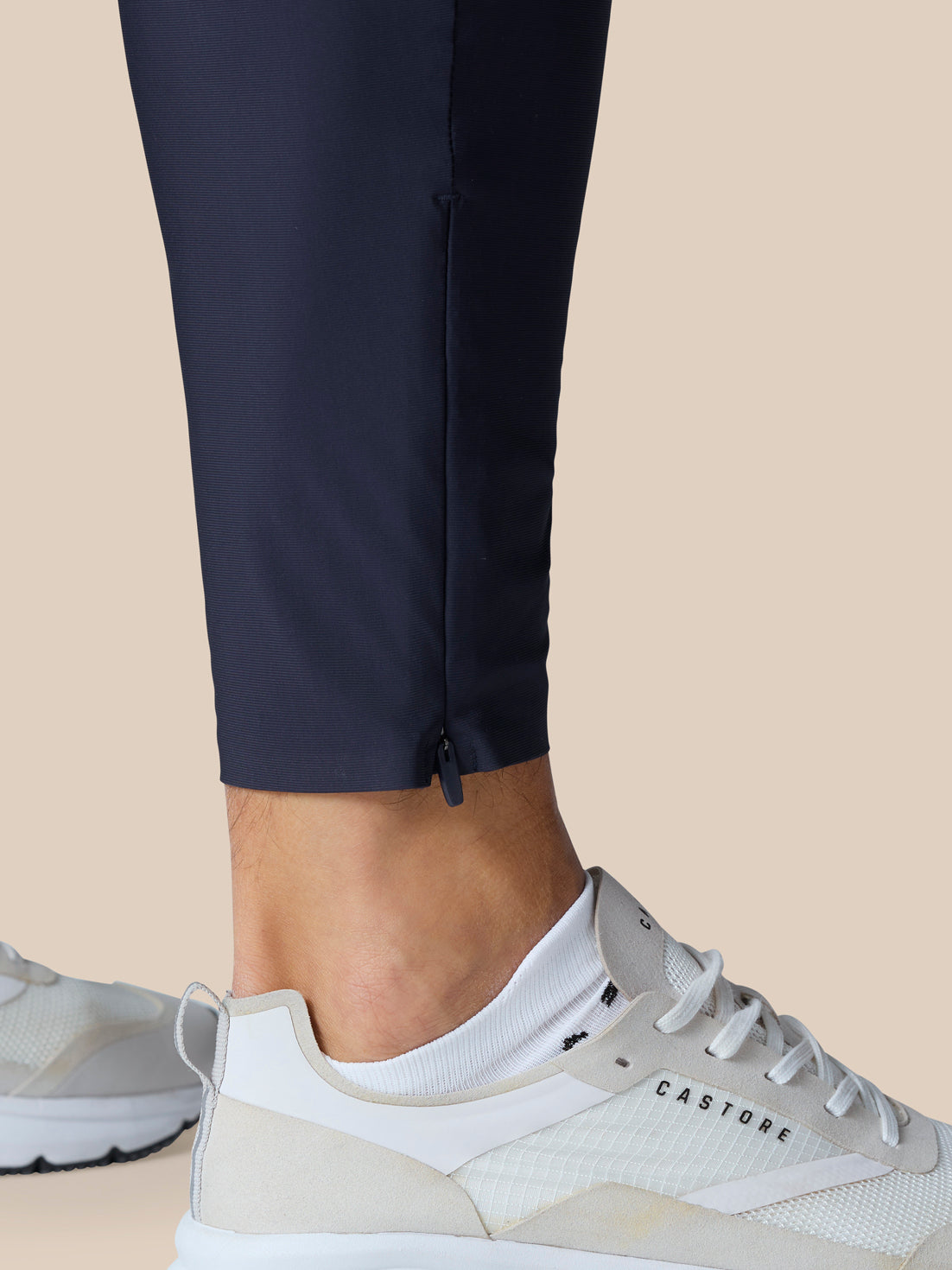 Lower leg of Zone Training Trousers in Midnight Navy with ankle zip and breathable panel, paired with white sneakers.