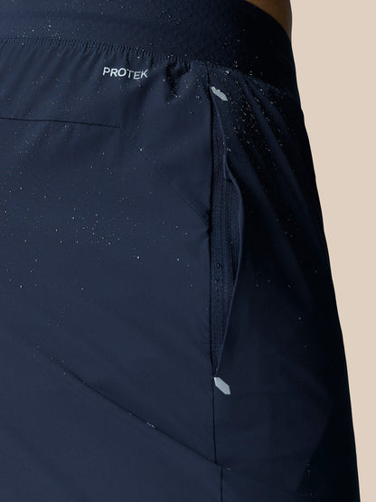 Back waist area of Zone Training Trousers in Midnight Navy with ProTek branding and concealed zip pocket; fabric shows water droplets.