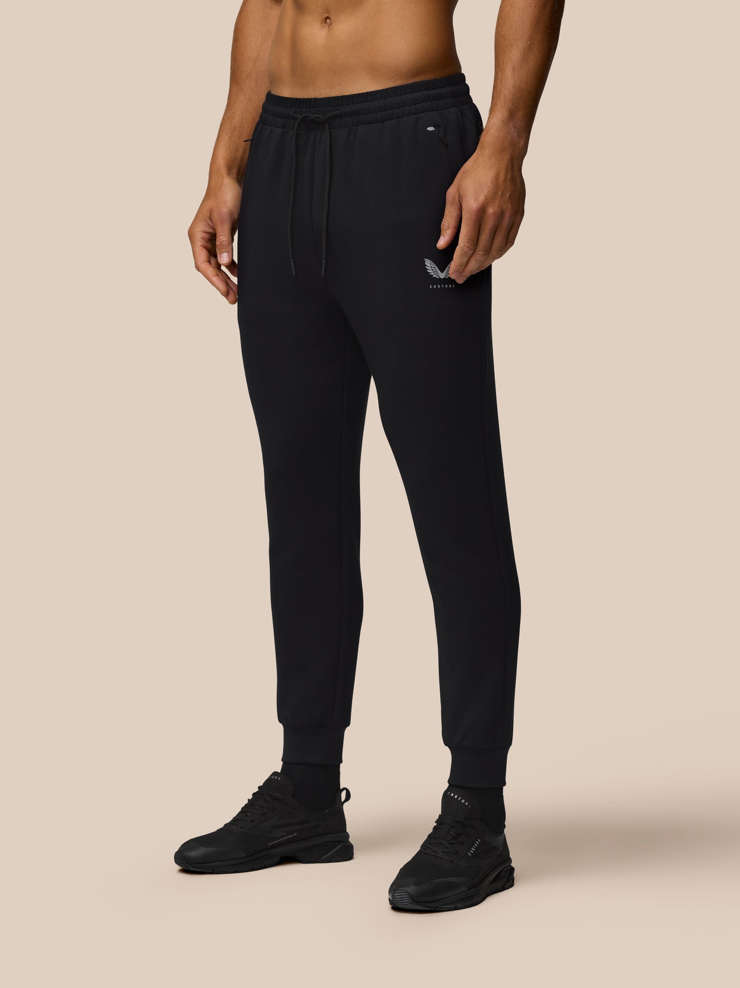 Male model wearing black Travel Joggers with a drawstring waist, zip pockets, and cuffed hems.