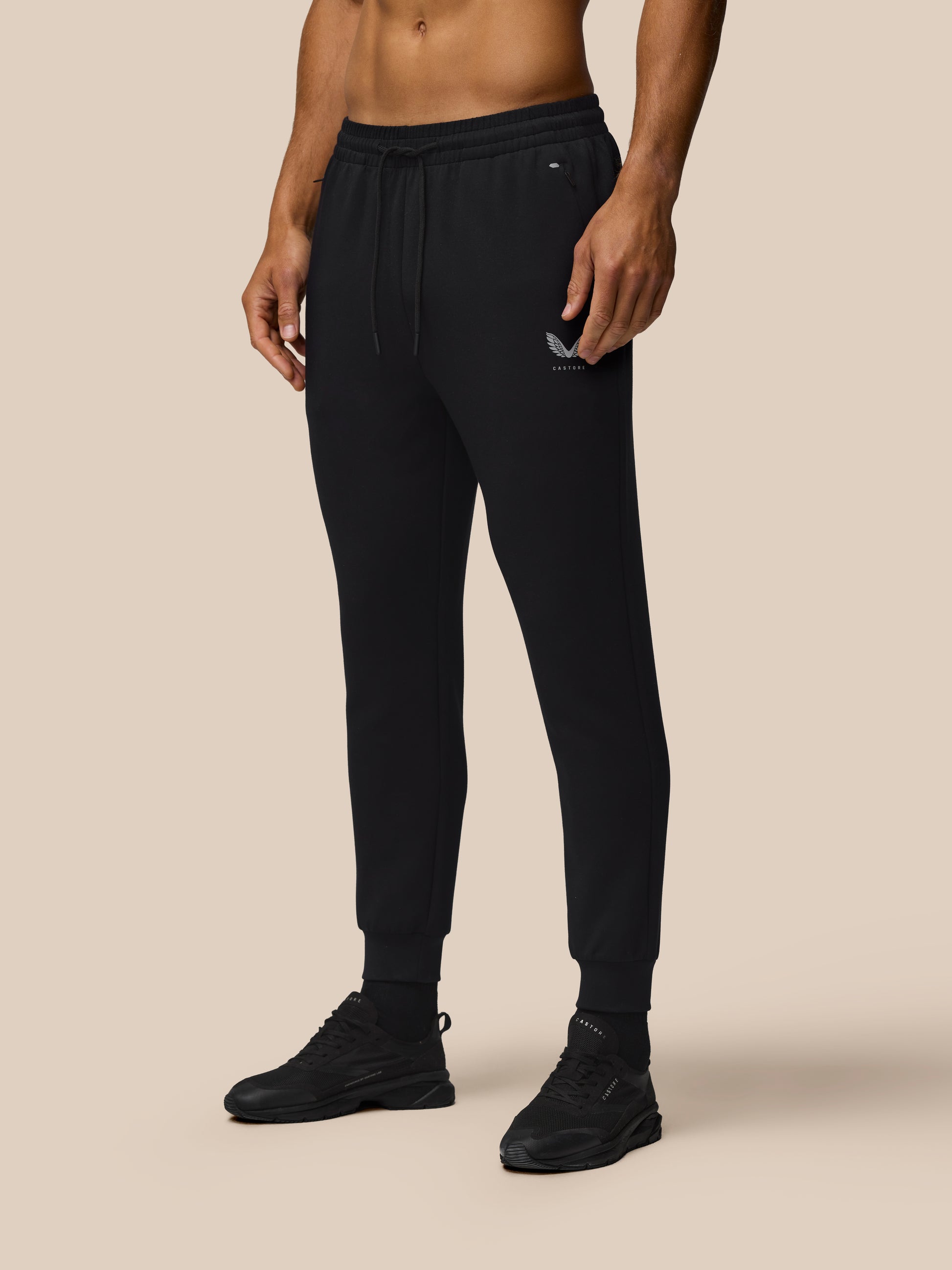 Male model wearing black Travel Joggers with a drawstring waist, zip pockets, and cuffed hems.
