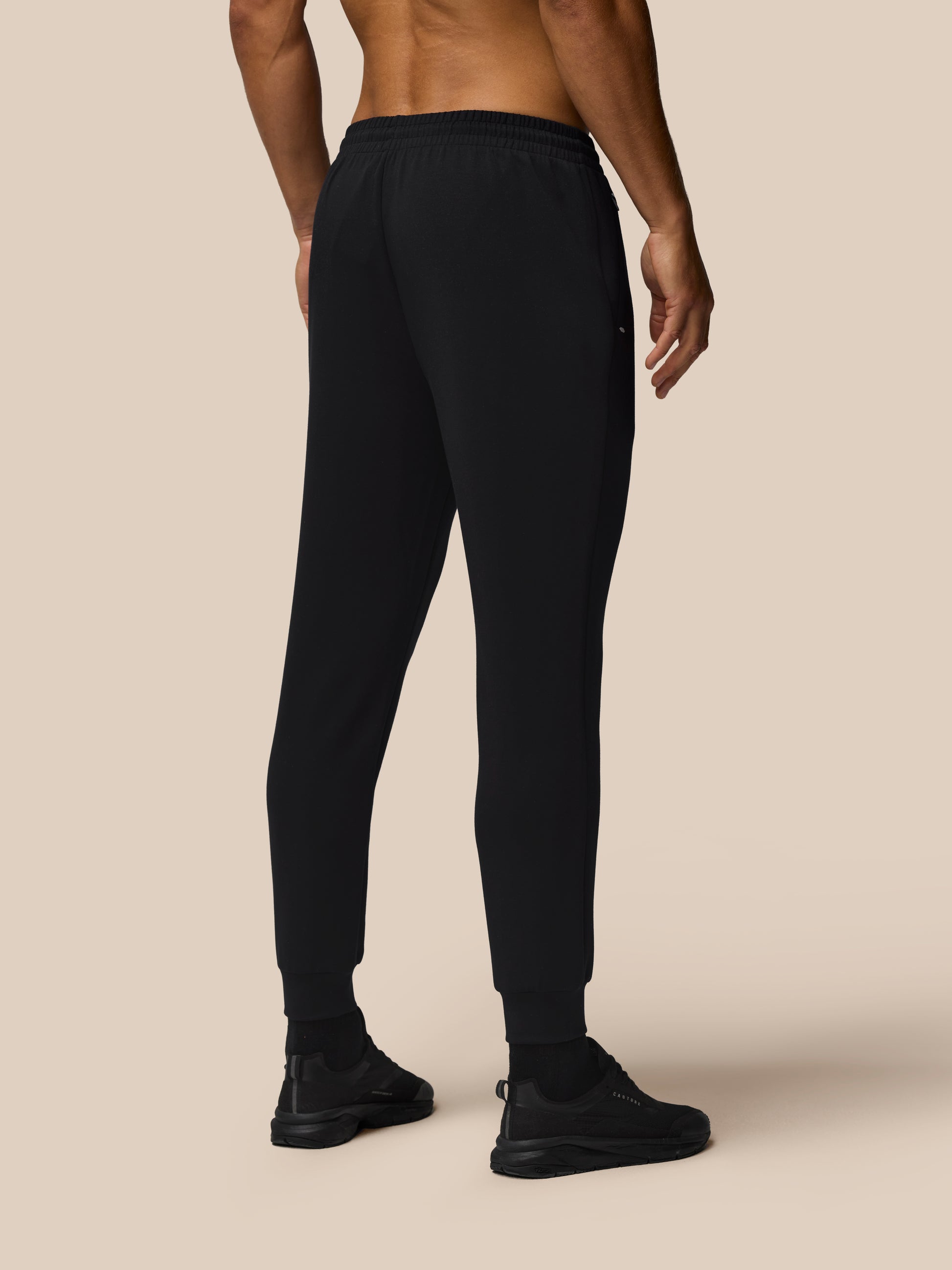 Back view of a man wearing black Travel Lifestyle Joggers with an elastic waistband and cuffed ankles