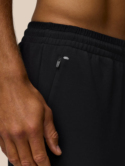 Close up of black travel joggers waistband showing elastic band and hip zip pocket.