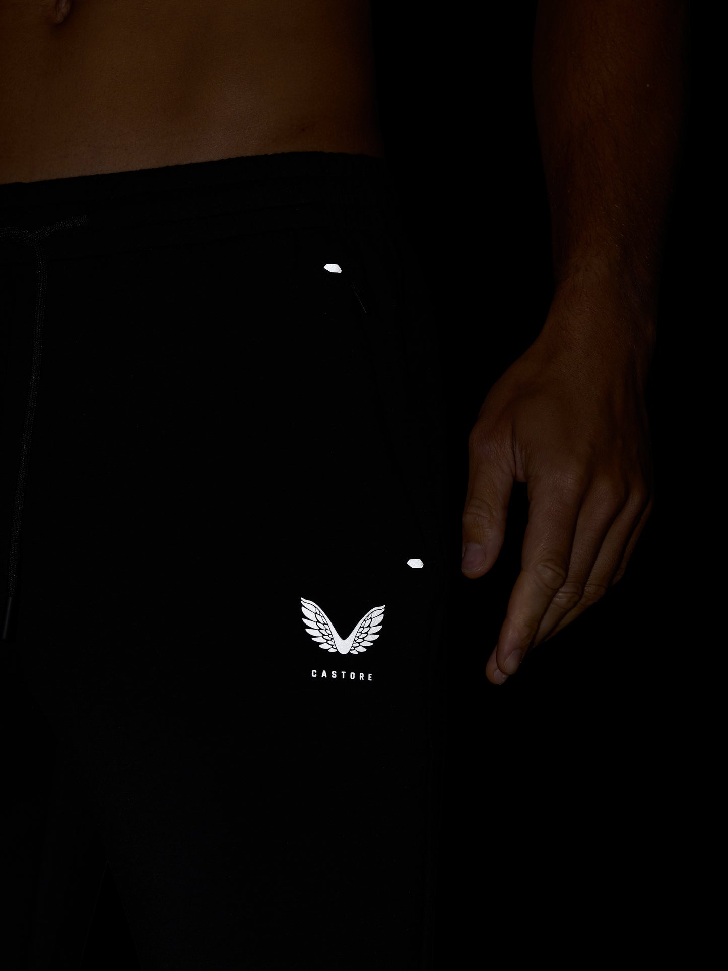 Close up of the waist area of Travel Lifestyle Joggers in black showing elastic waistband and Castore logo on leg