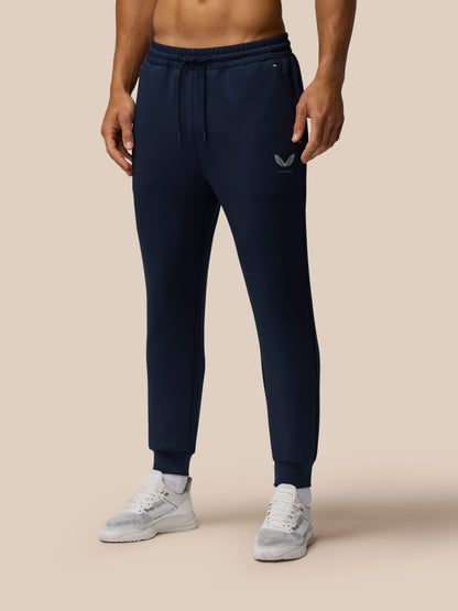 Model wearing navy Travel Lifestyle Joggers with elastic drawstring waist, tapered cuffs and Castore logo on the thigh, paired with white sneakers