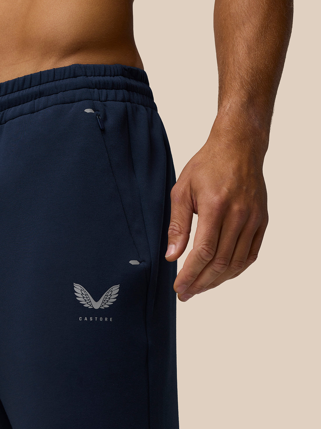 Close up of navy Travel Lifestyle Joggers showing concealed zip pocket and Castore logo at the hip.