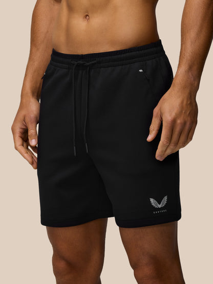 Close up of black travel shorts with elastic waistband, drawcord, concealed zip pocket, and Castore emblem at the hem.