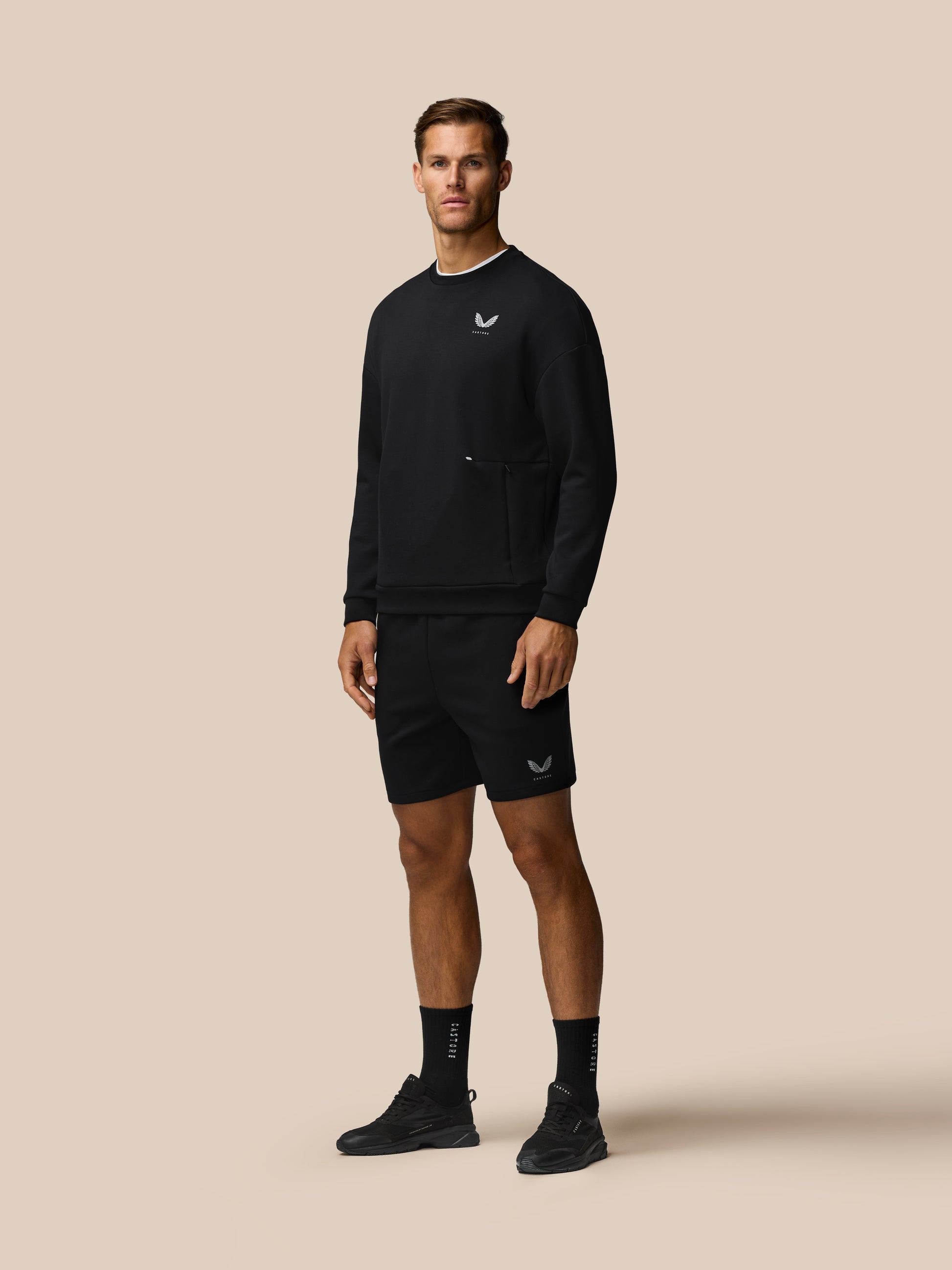 Model wearing black Travel Lifestyle Shorts with concealed zip pockets and Castore logo on leg