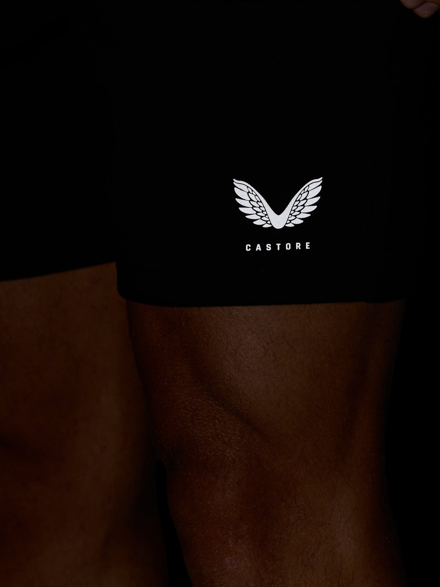 Close-up of black Travel Lifestyle Shorts with a white Castore wing logo near the hem