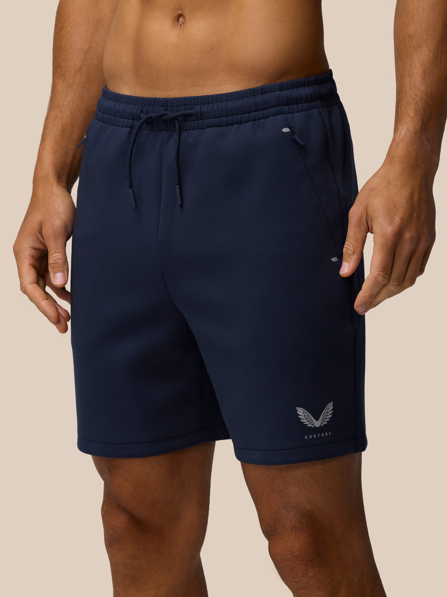 Front view of navy Travel Lifestyle Shorts with elastic drawstring waist concealed zip pocket and Castore logo