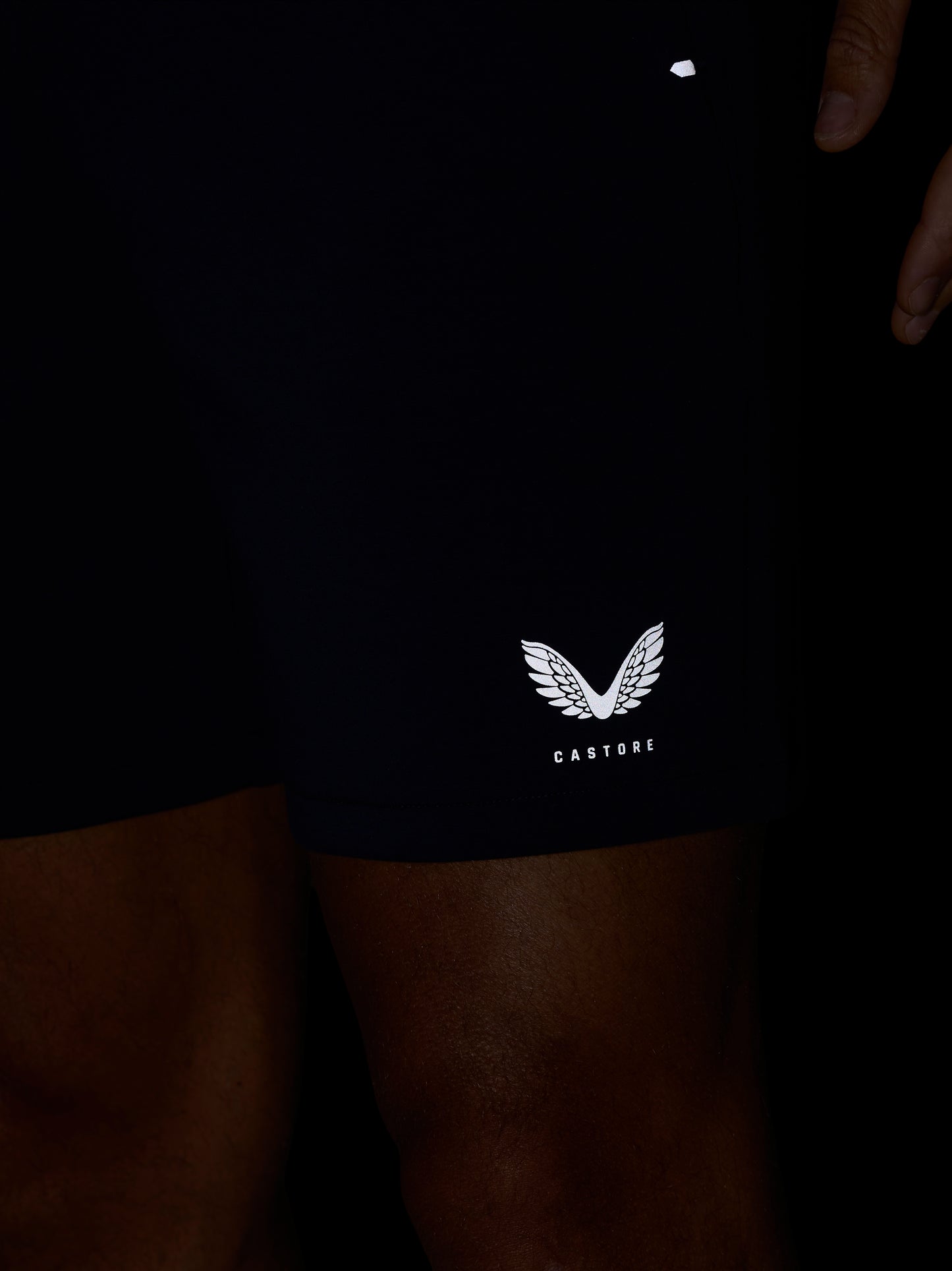 Close-up of navy shorts leg displaying the white Castore wing logo