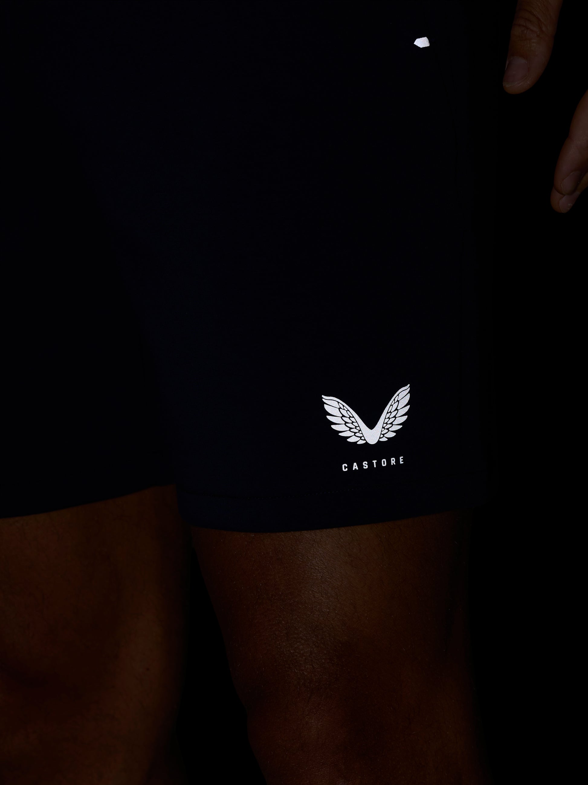 Close-up of navy shorts leg displaying the white Castore wing logo