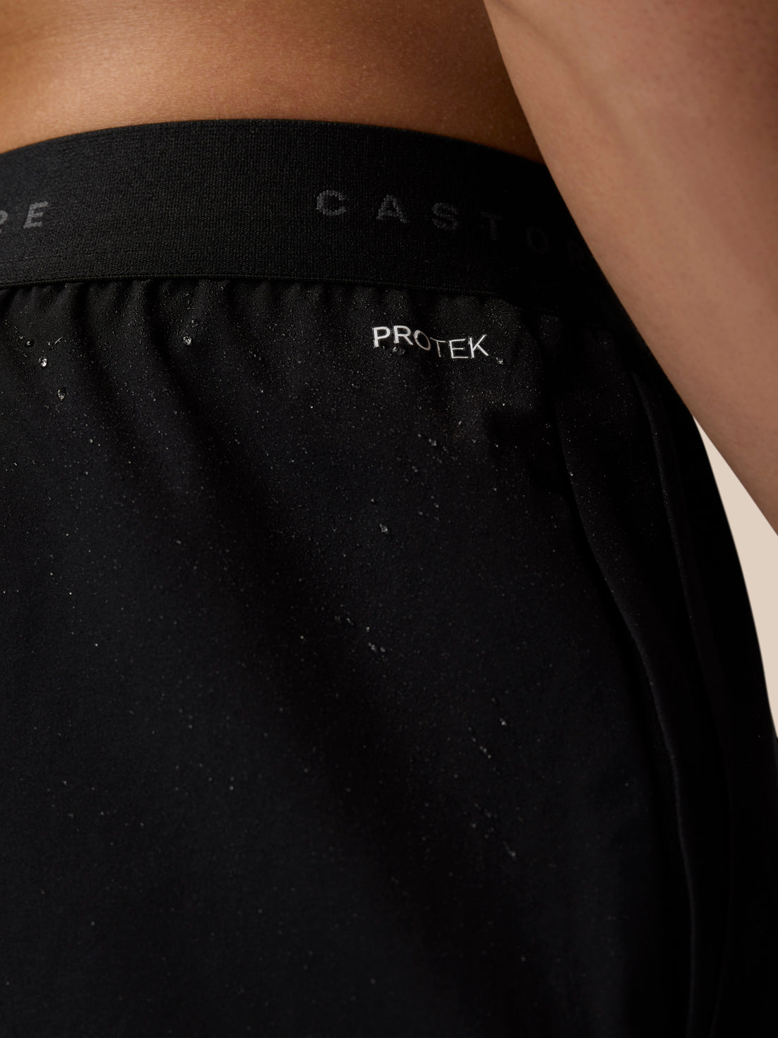 Close-up of black Adapt Training Shorts waistband with PROTEK label and Castore branding.