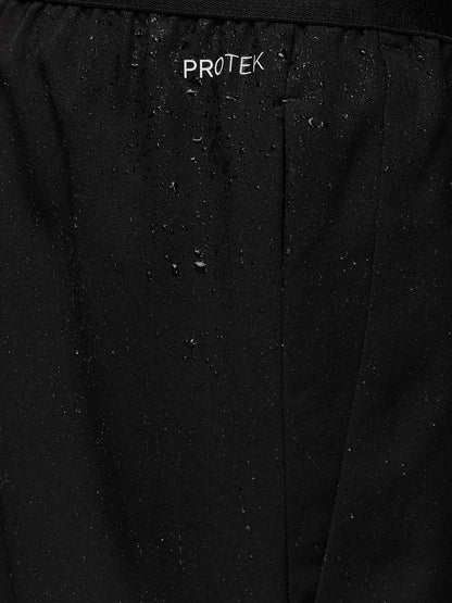 Close-up of black Adapt Training Shorts fabric with water droplets and PROTEK branding on the waistband