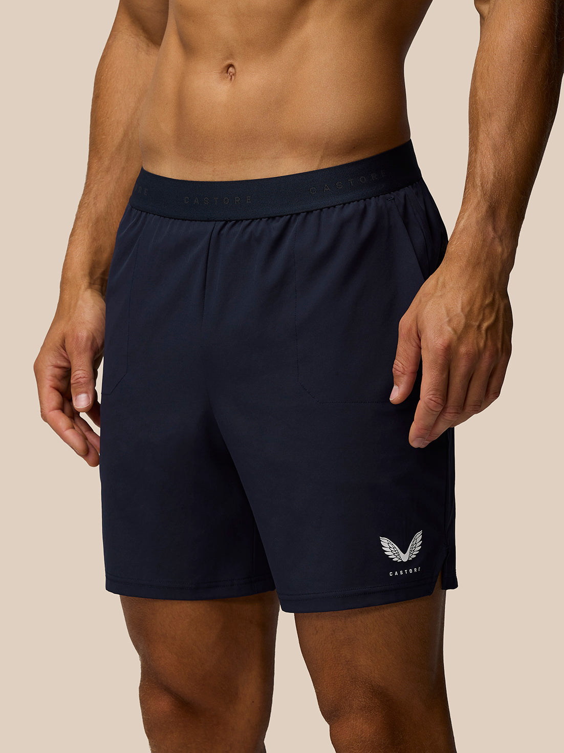 Adapt Training Shorts in midnight navy on a model, showing elastic waistband with drawcords and side pockets with Castore branding on the right thigh.