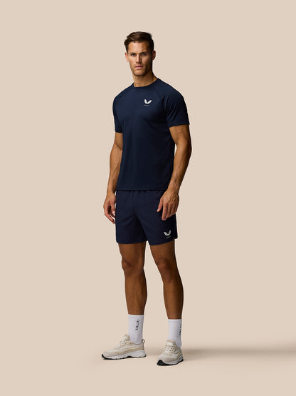 Male model wearing midnight navy Adapt Training Shorts and matching top with Castore branding on chest and thigh