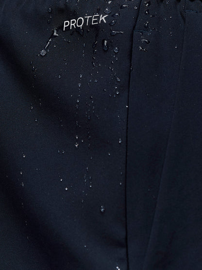 Close-up of midnight navy Adapt Training Short fabric showing water beading and PROTEK branding.
