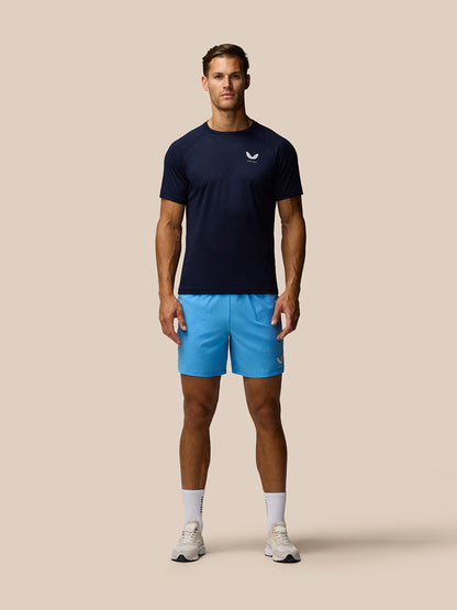 Male model wearing Adapt Training Shorts in Cool Blue with a navy top, front view.
