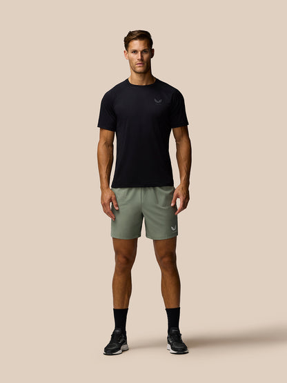 Full body front view of a male model in Thyme Mint Adapt Training Shorts with Castore logo on the left leg and a black top