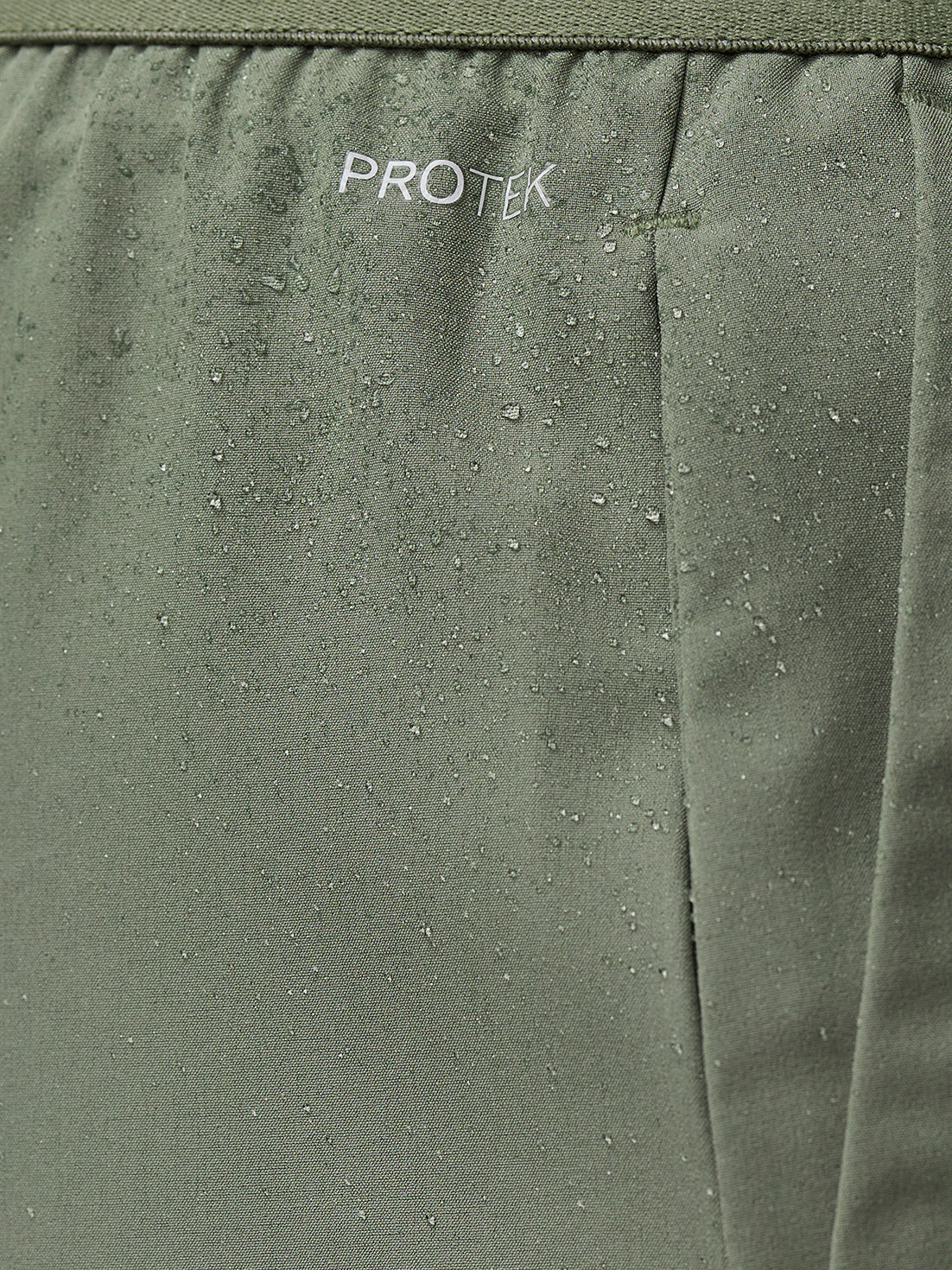 Close up of thyme mint Adapt Training Shorts fabric with water droplets and ProTek branding.