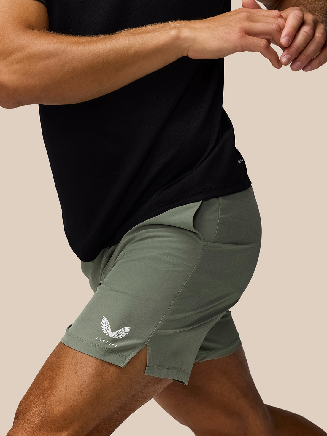 Side view of a male model wearing Thyme Mint Adapt Training Shorts with a logo on the left leg