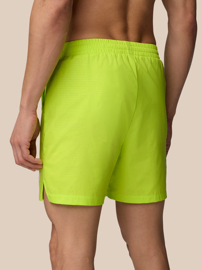 Back view of acid lime Adapt Swim Shorts with elastic waistband and a side zip pocket