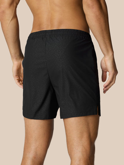 Rear view of black Adapt Swim Shorts on a model featuring an elastic waistband and grid texture.