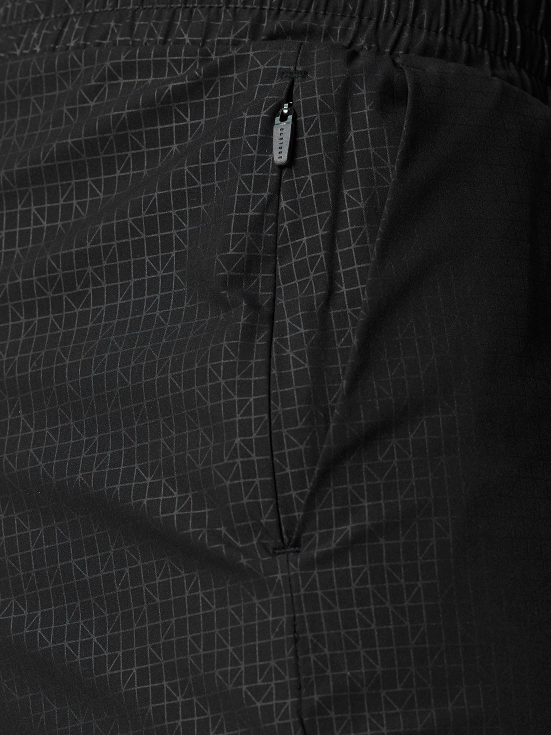 Close-up of black Adapt Swim Shorts showing the zip pocket and grid fabric pattern.