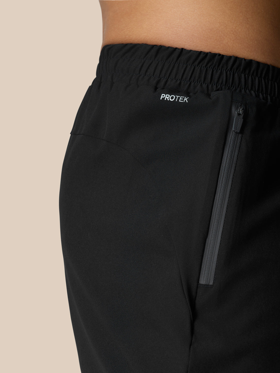Side view of black Flow Training Shorts with a vertical zip pocket and ProTek branding on the waistband