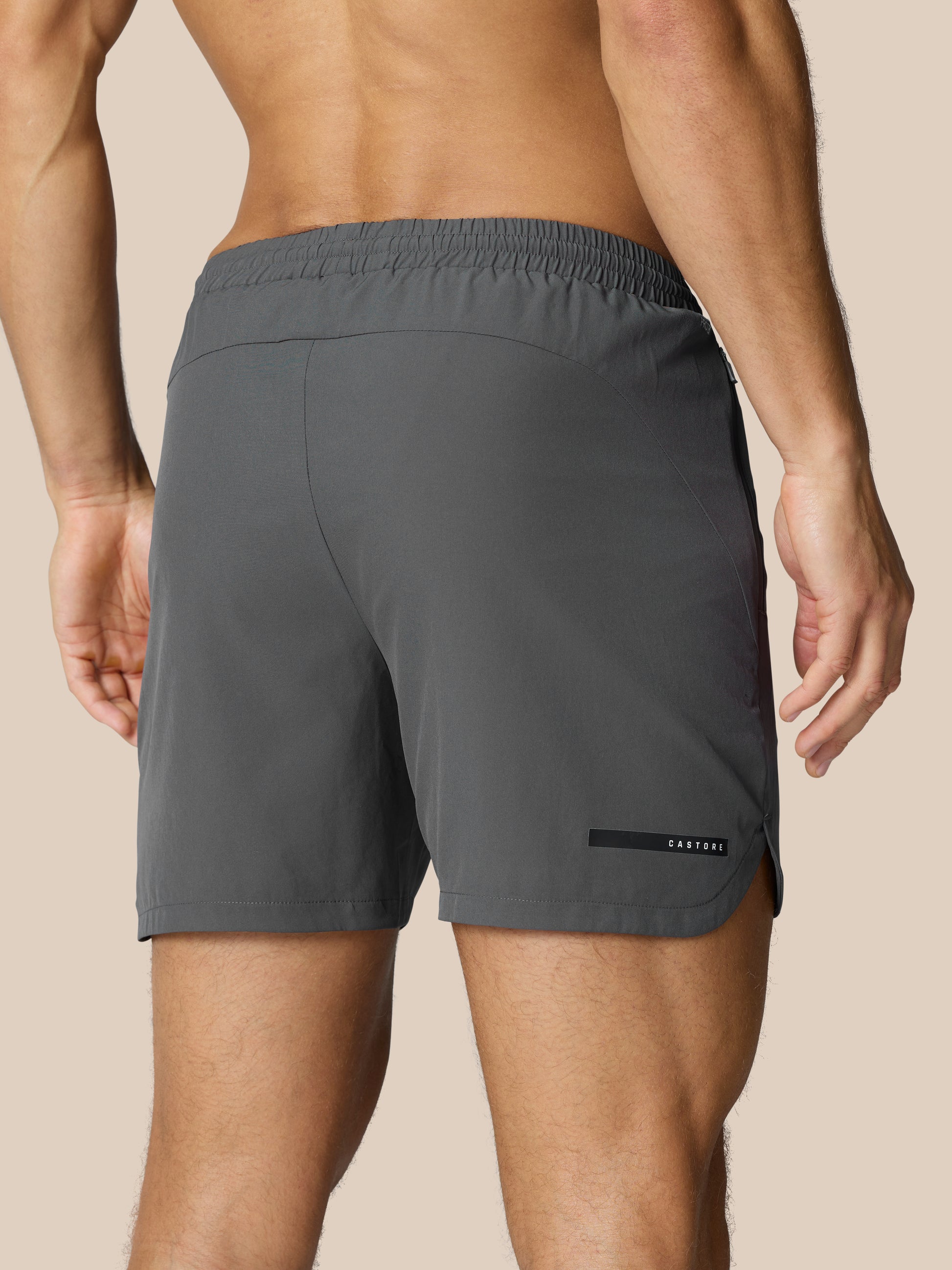 Back view of a man wearing Flow Training Shorts Gunmetal with an elastic waistband and Castore label.
