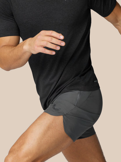 Side view of a man wearing gunmetal Flow Training Shorts with a close fit and subtle logo at the hem