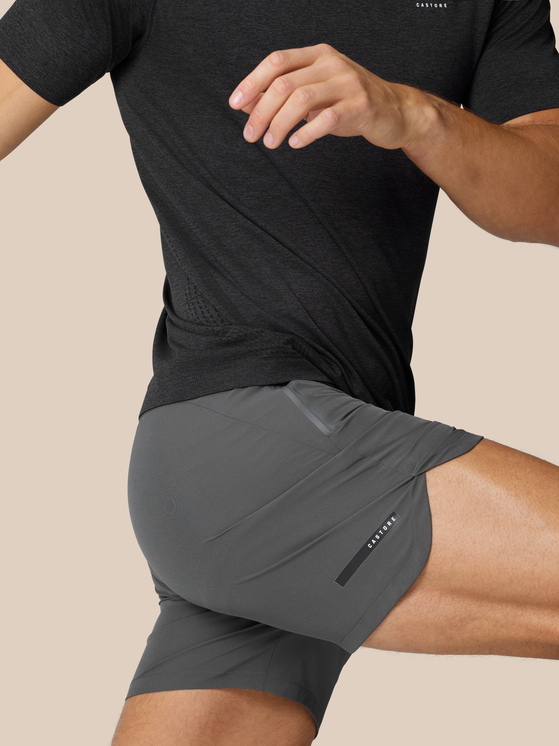 Man wearing gunmetal Flow Training Shorts with a side zip pocket and Castore branding.