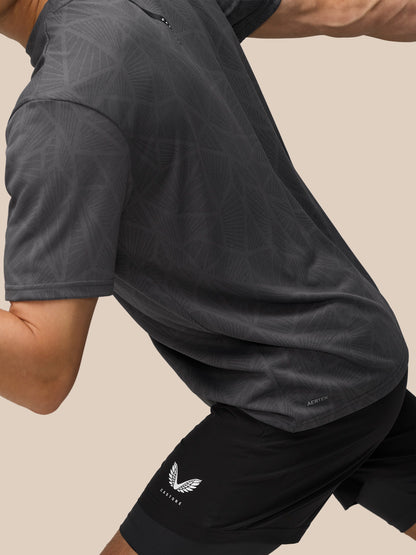 Side view of a model in a dark patterned T shirt and Flow 2-in-1 shorts with Castore branding on the thigh