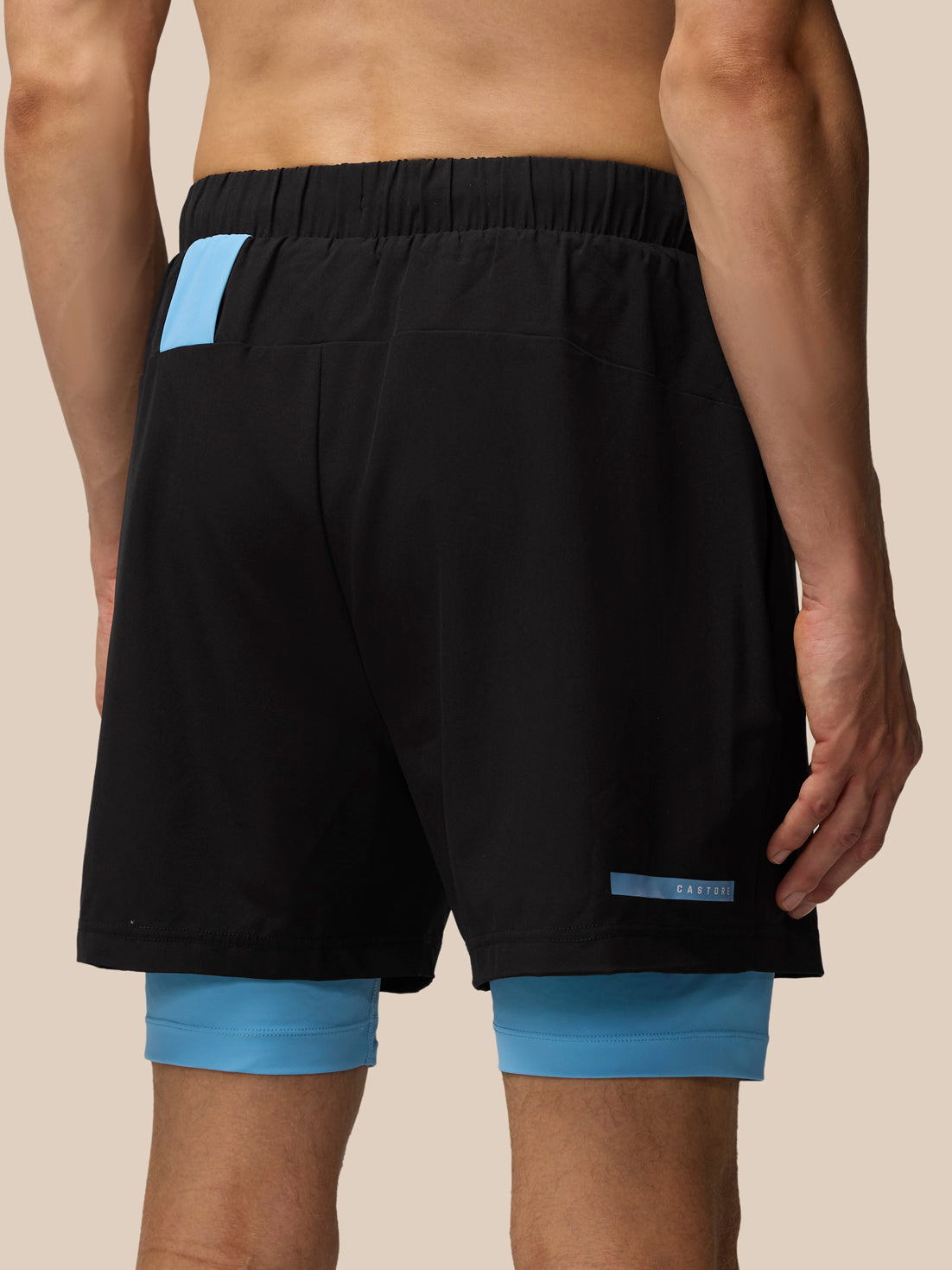 Black Flow 2-in-1 shorts with blue undershorts beneath and Castore logo on the lower front leg