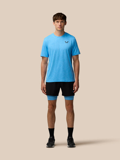 Full body shot of a male model wearing Flow 2-in-1 Shorts black with blue undershorts and a light blue patterned T shirt.