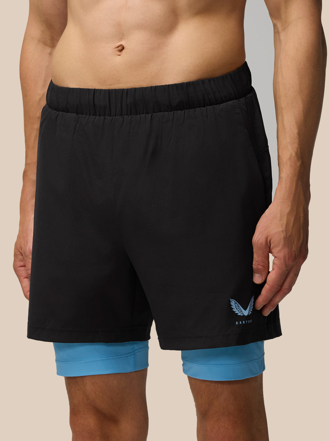 Black Flow 2-in-1 shorts with blue undershorts visible below and a blue pocket accent with the Castore logo