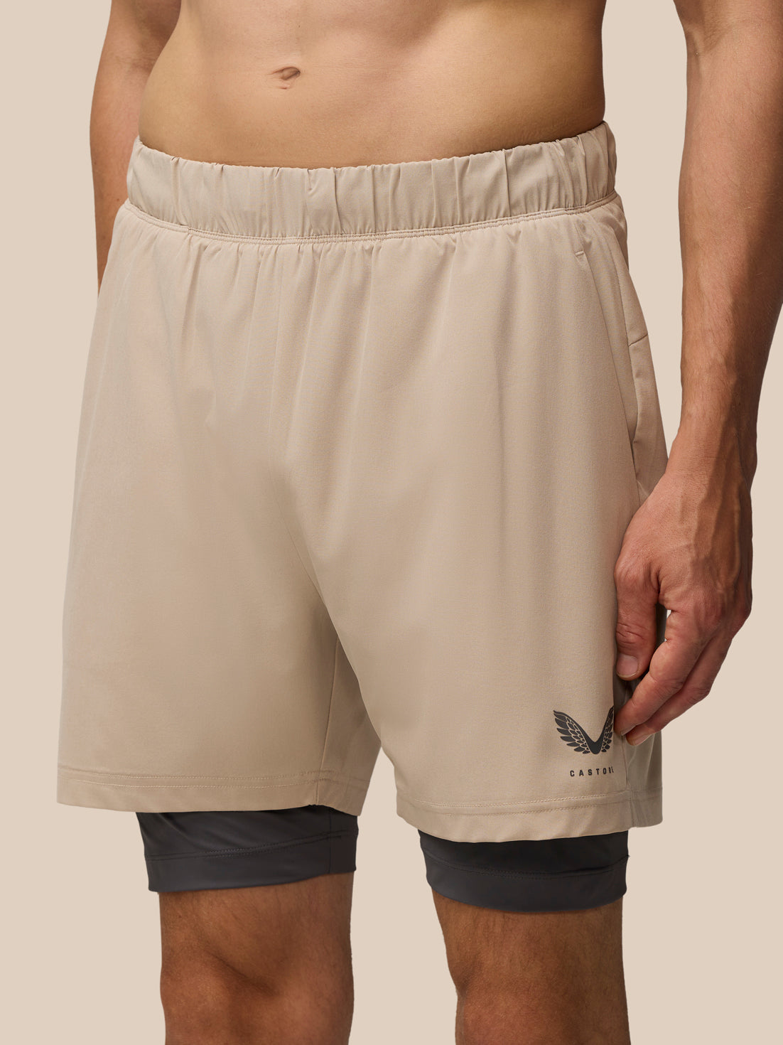 Beige Flow 2-in-1 Shorts with inner black undershorts and a Castore wing logo at the hem.