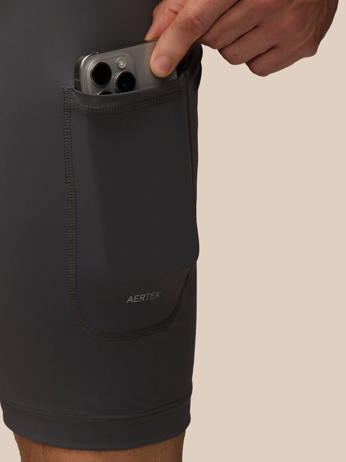 Close up of the side pocket on Flow 2-in-1 Beige shorts with a smartphone tucked inside