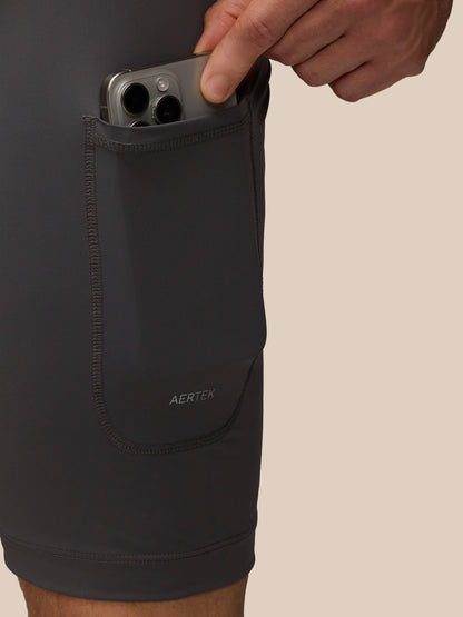 Close up of the side pocket on Flow 2-in-1 Beige shorts with a smartphone tucked inside