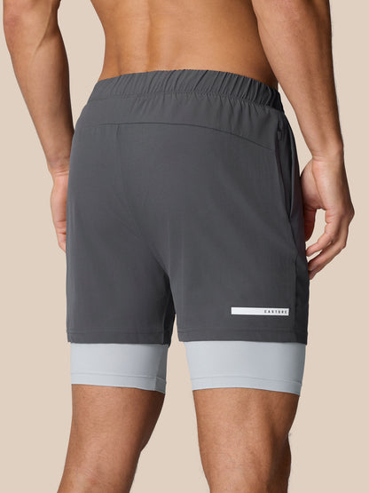 Back view of dark grey Flow Training 2-in-1 shorts with inner layer peeking at the hem and Castore logo