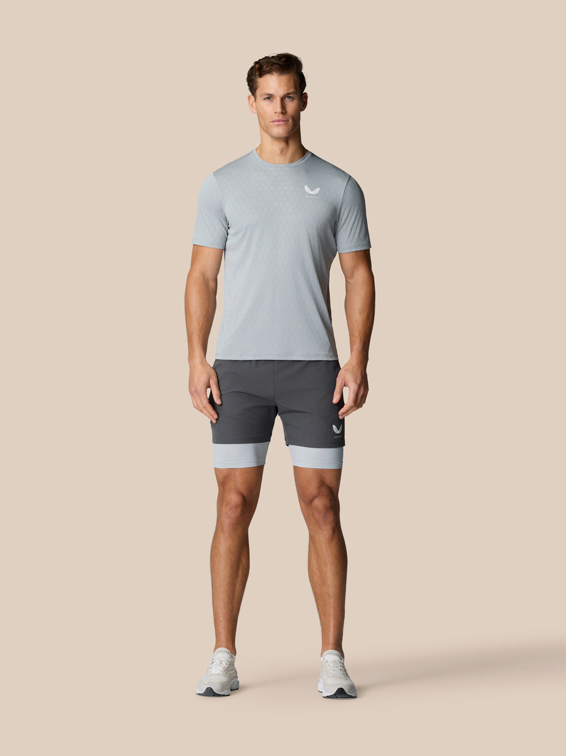 Male model wearing Flow Training 2-In-1 Short in mid grey with a lighter underlayer visible.