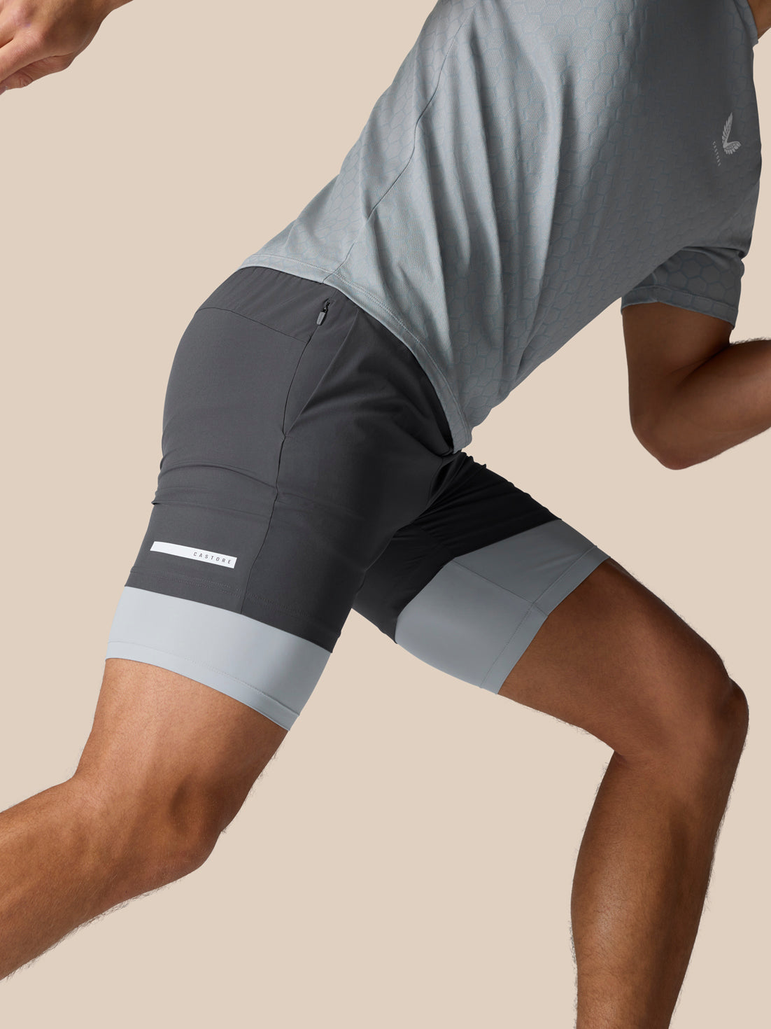 Side view of Flow Training 2-In-1 Shorts with dark grey body and light grey leg bands and Castore logo on back thigh