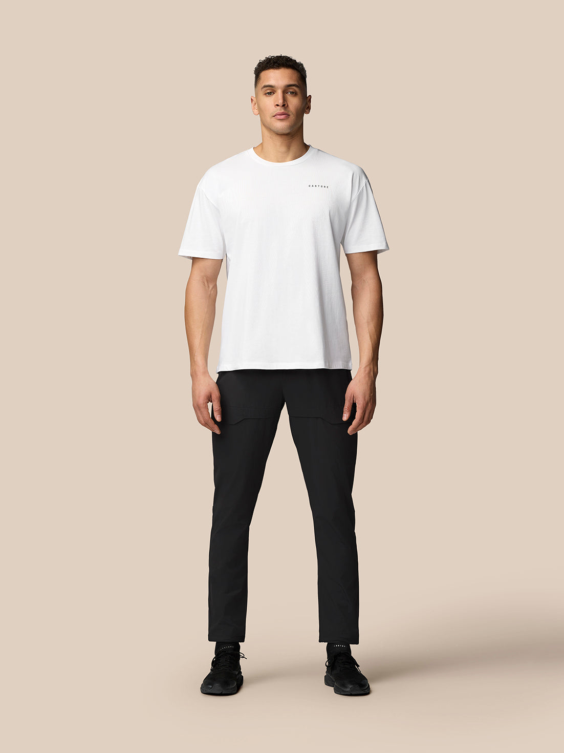 Full body front view of male model wearing white T shirt and black Flex Lifestyle Cargo Trousers showcasing cargo pockets.